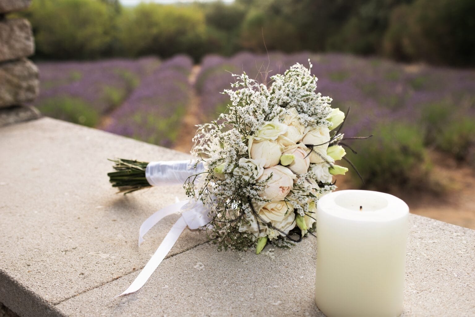Bouquet de la mariée posé sur un muret, une bougie à coté et de la lavande en arrière plan